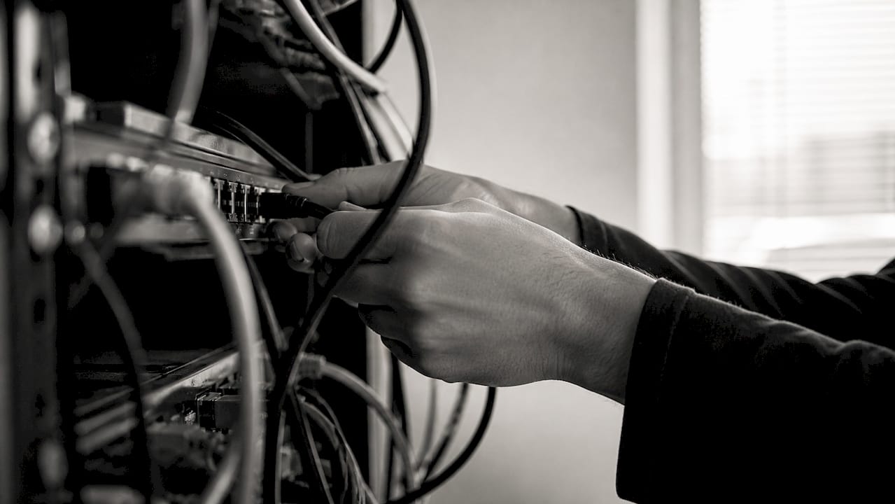 Des mains connectent un câble Ethernet à un switch réseau.